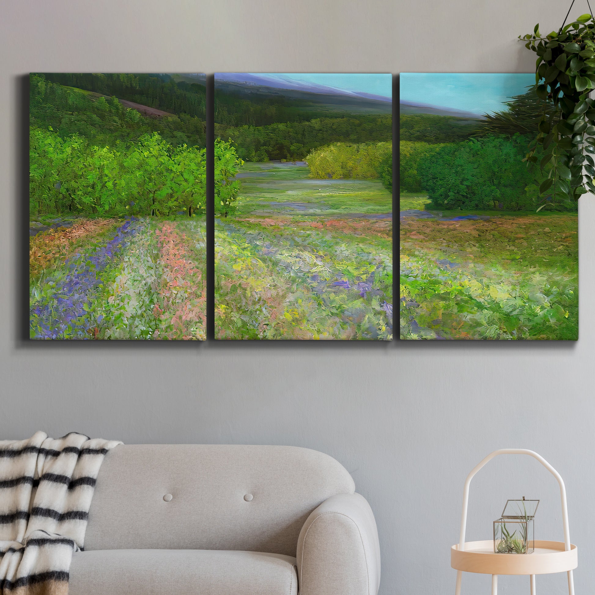 Three-panel canvas wall art featuring fresh spring meadow landscape, displayed in a modern living room above a sofa.