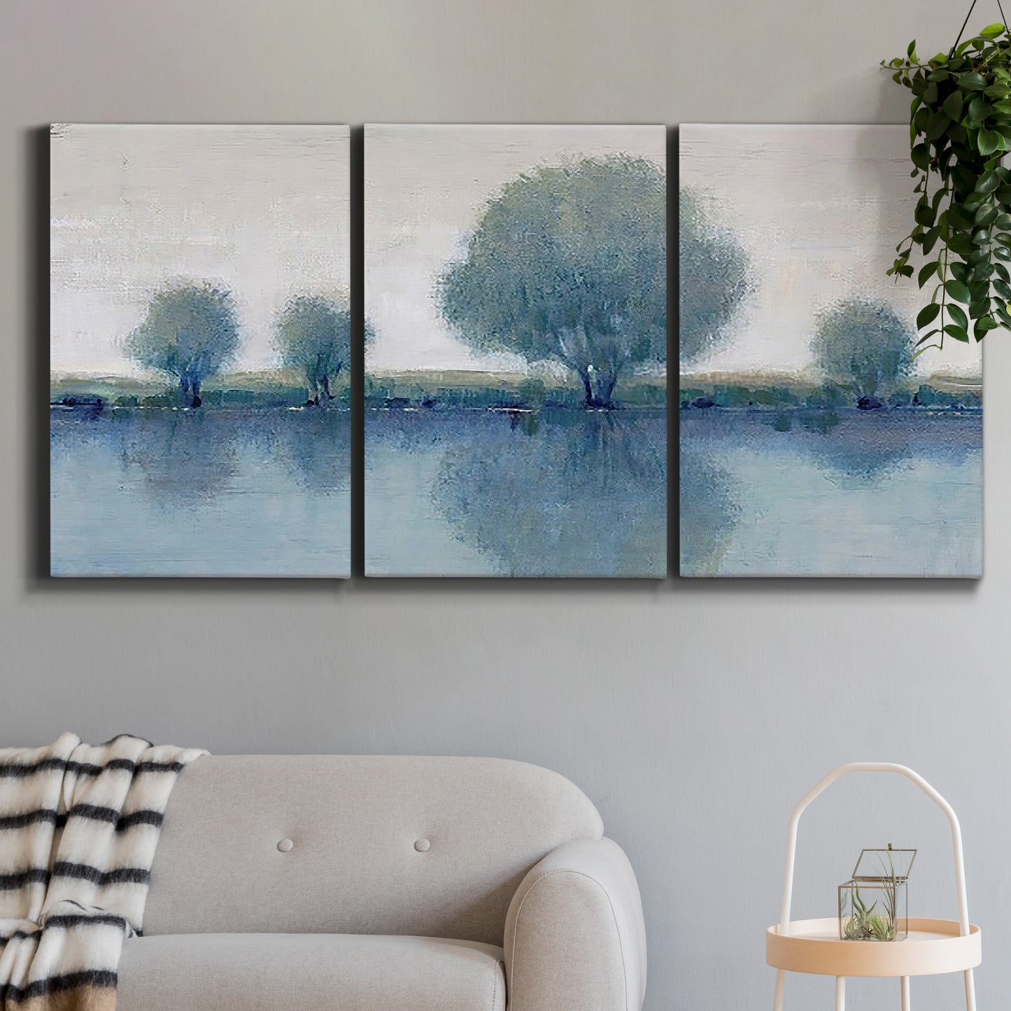 Three-panel canvas wall art featuring calm afternoon river reflection, displayed in a modern living room above a sofa.