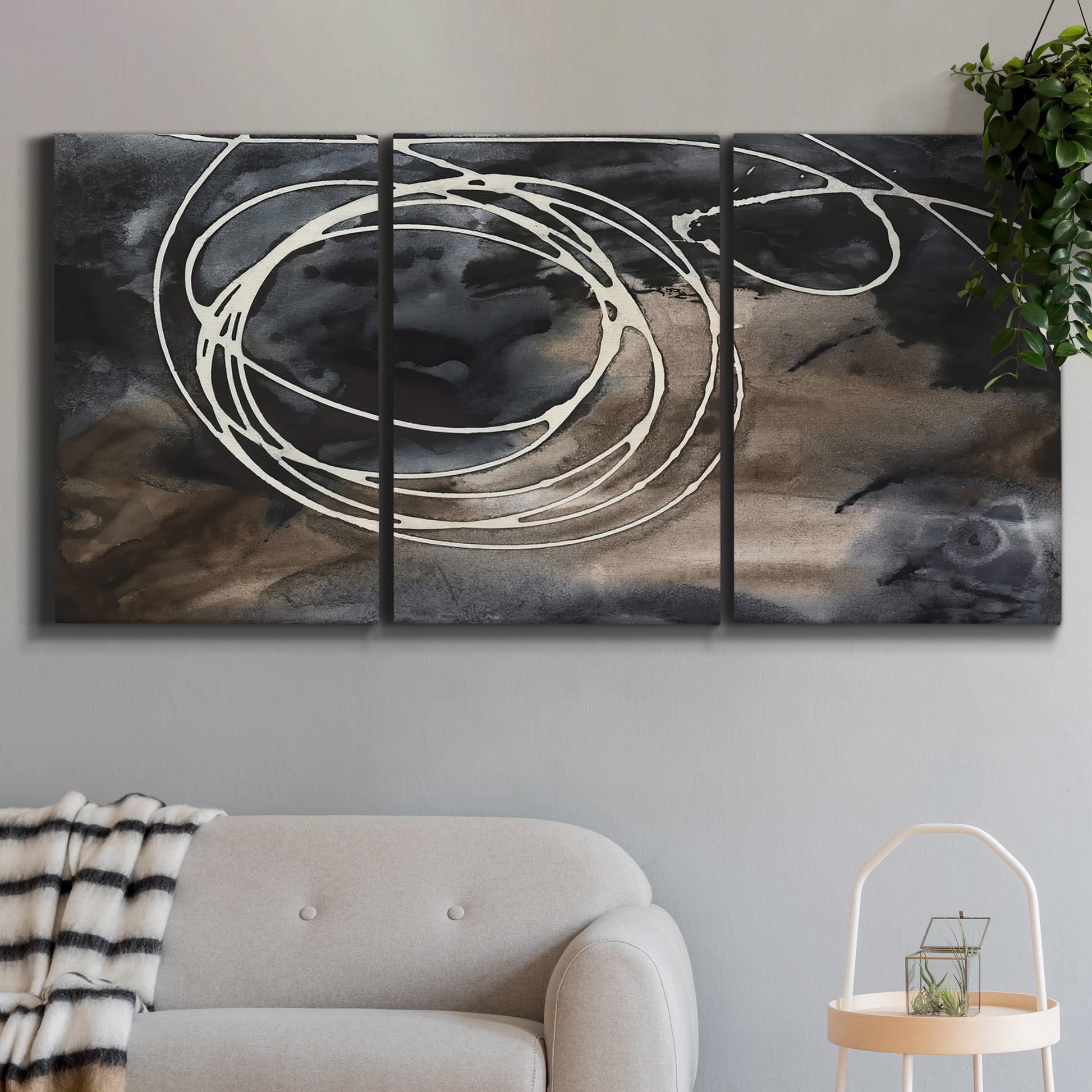 Three-panel canvas wall art featuring dark swirling abstract motion, displayed in a modern living room above a sofa.