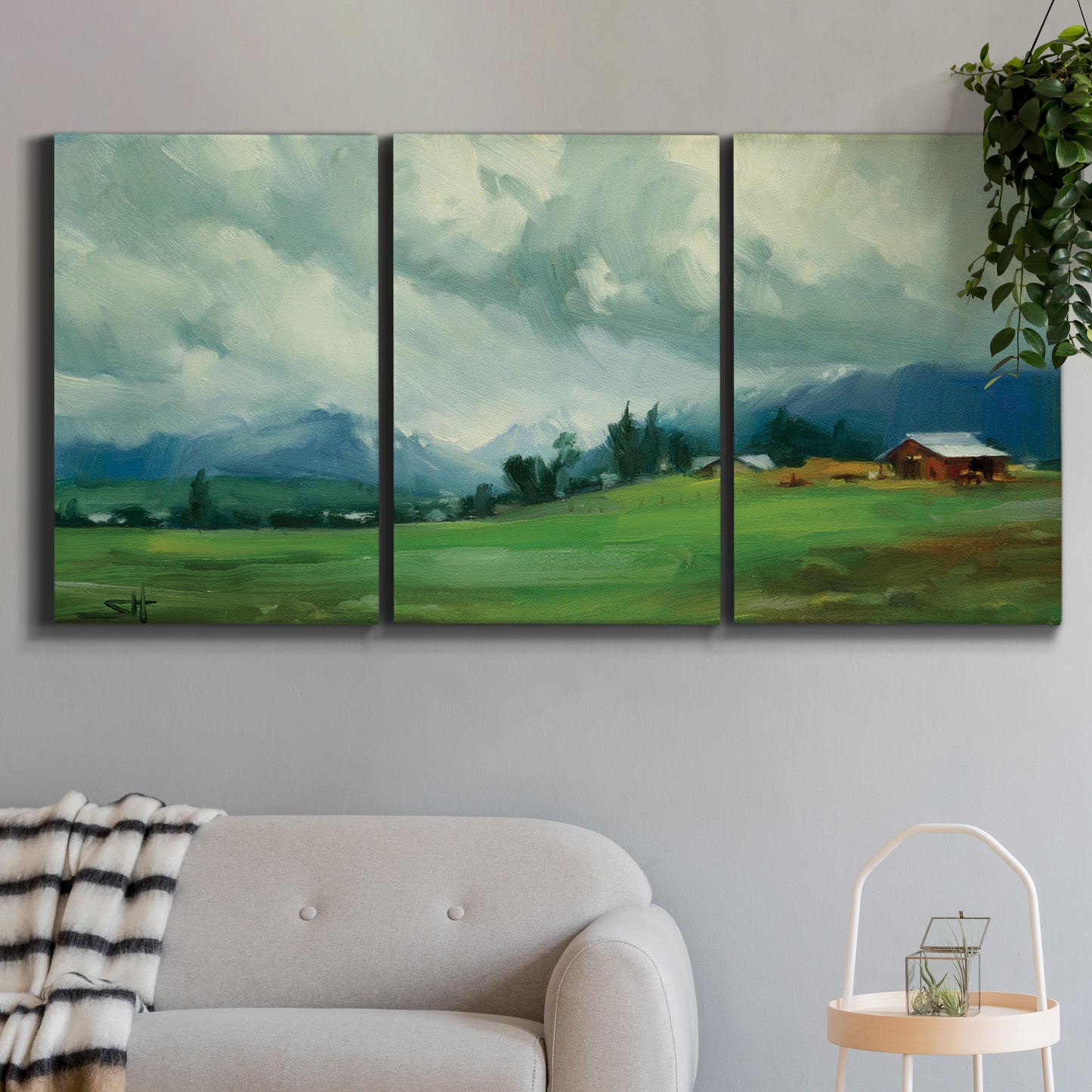 Three-panel canvas wall art featuring wide pastoral valley landscape, displayed in a modern living room above a sofa.
