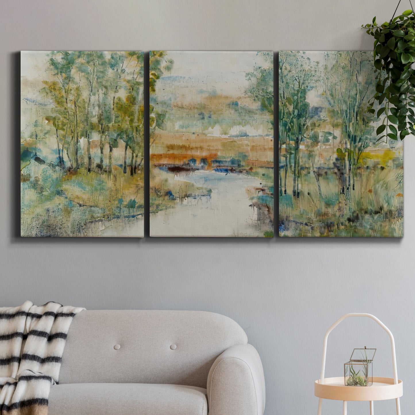 Three-panel canvas wall art featuring trees lining quiet creek, displayed in a modern living room above a sofa.