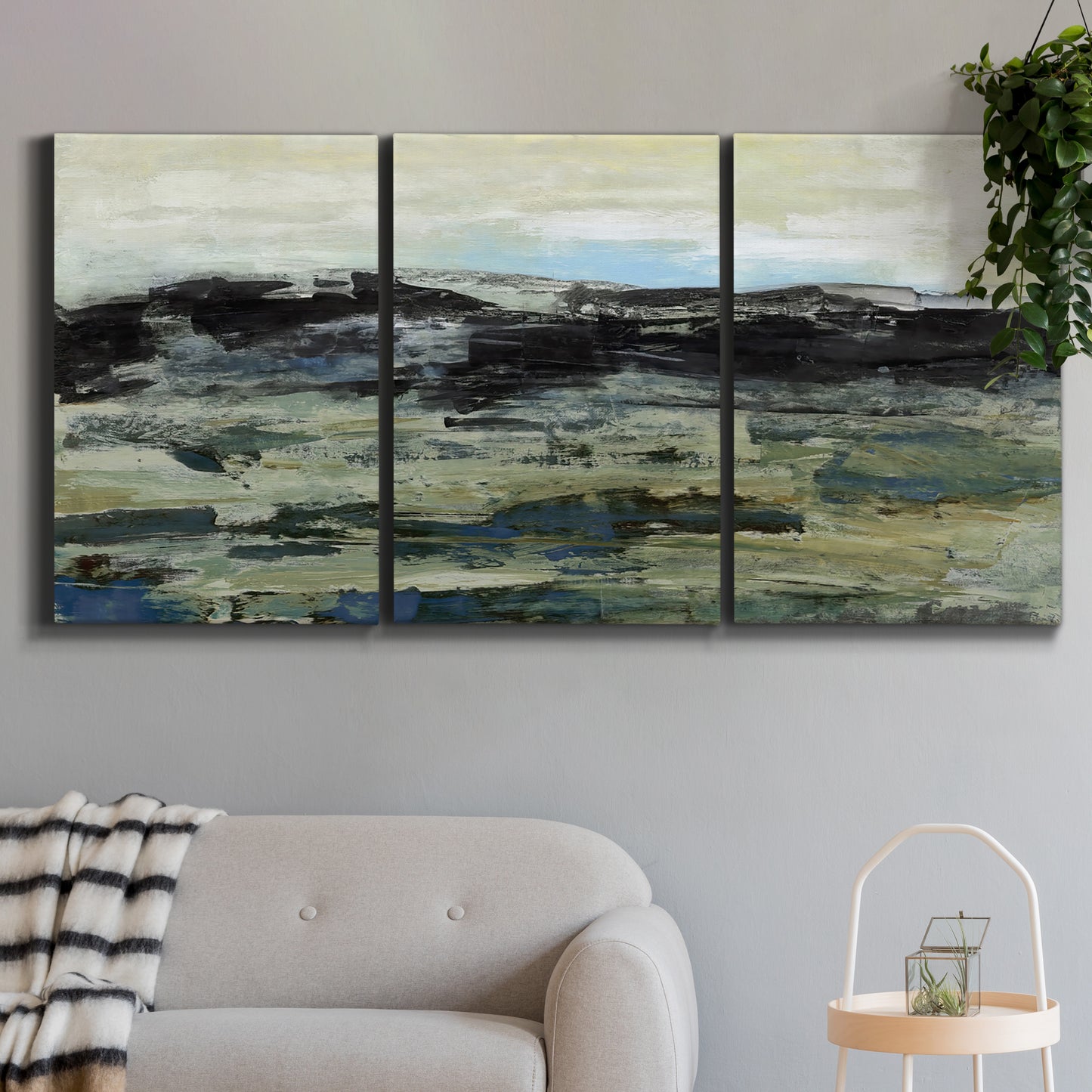 Three-panel canvas wall art featuring muted abstract landscape study, displayed in a modern living room above a sofa.