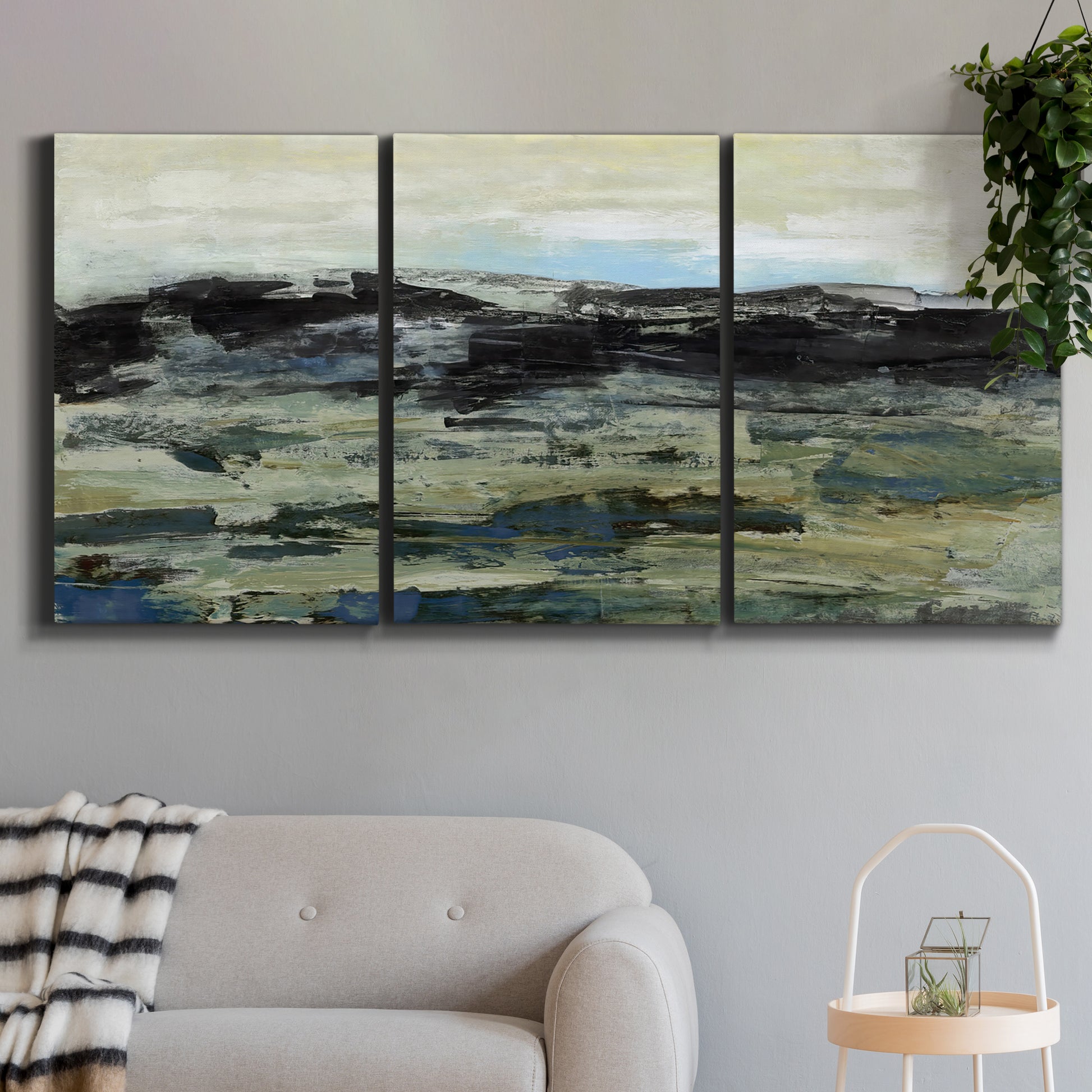 Three-panel canvas wall art featuring muted abstract landscape study, displayed in a modern living room above a sofa.
