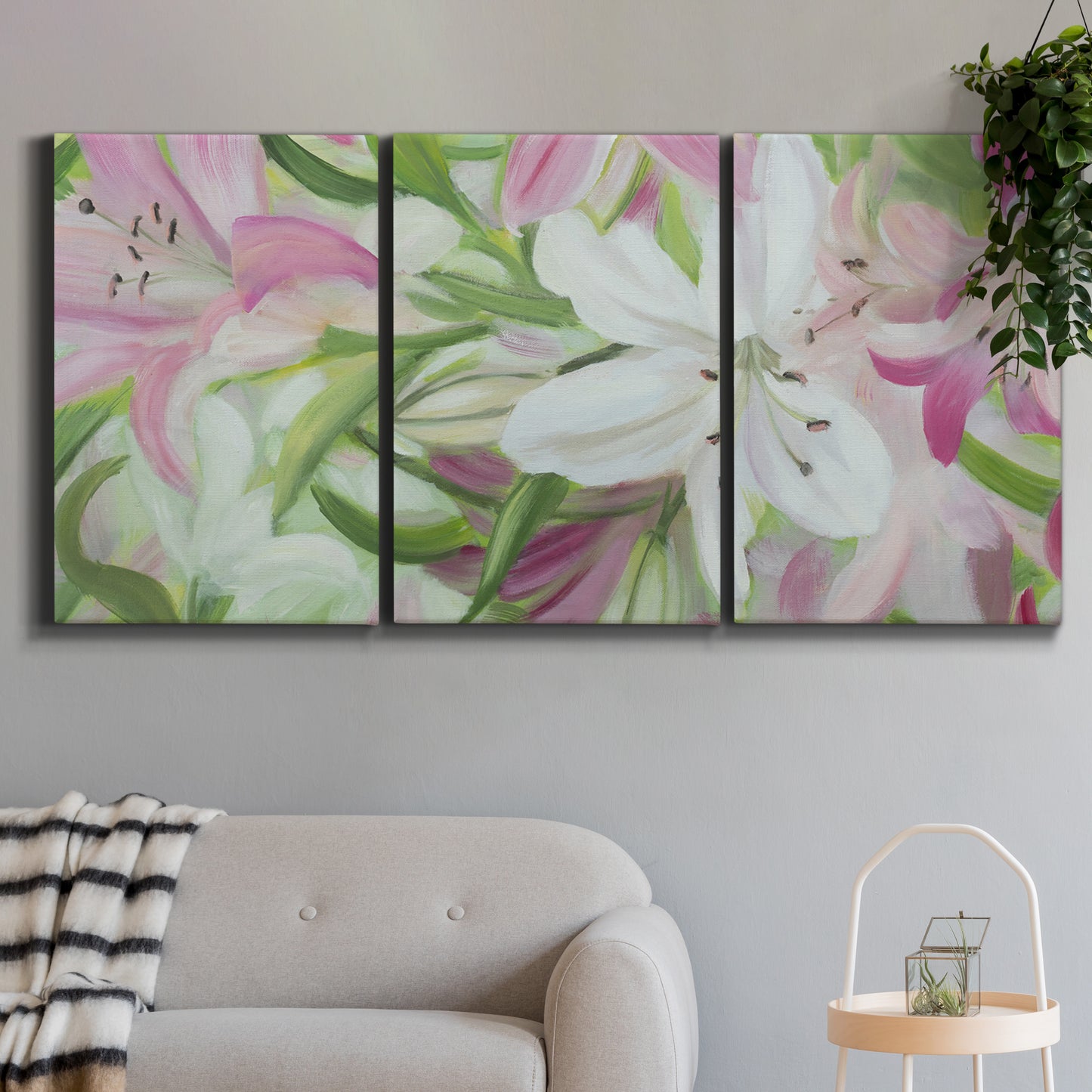 Three-panel canvas wall art featuring pink and white lilies botanical study, displayed in a modern living room above a sofa.