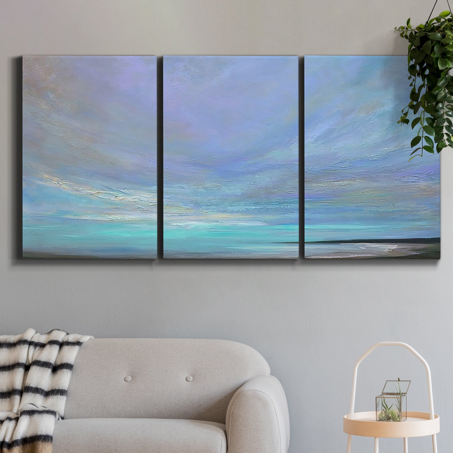Three-panel canvas wall art featuring coastal shoreline with gentle surf, displayed in a modern living room above a sofa.