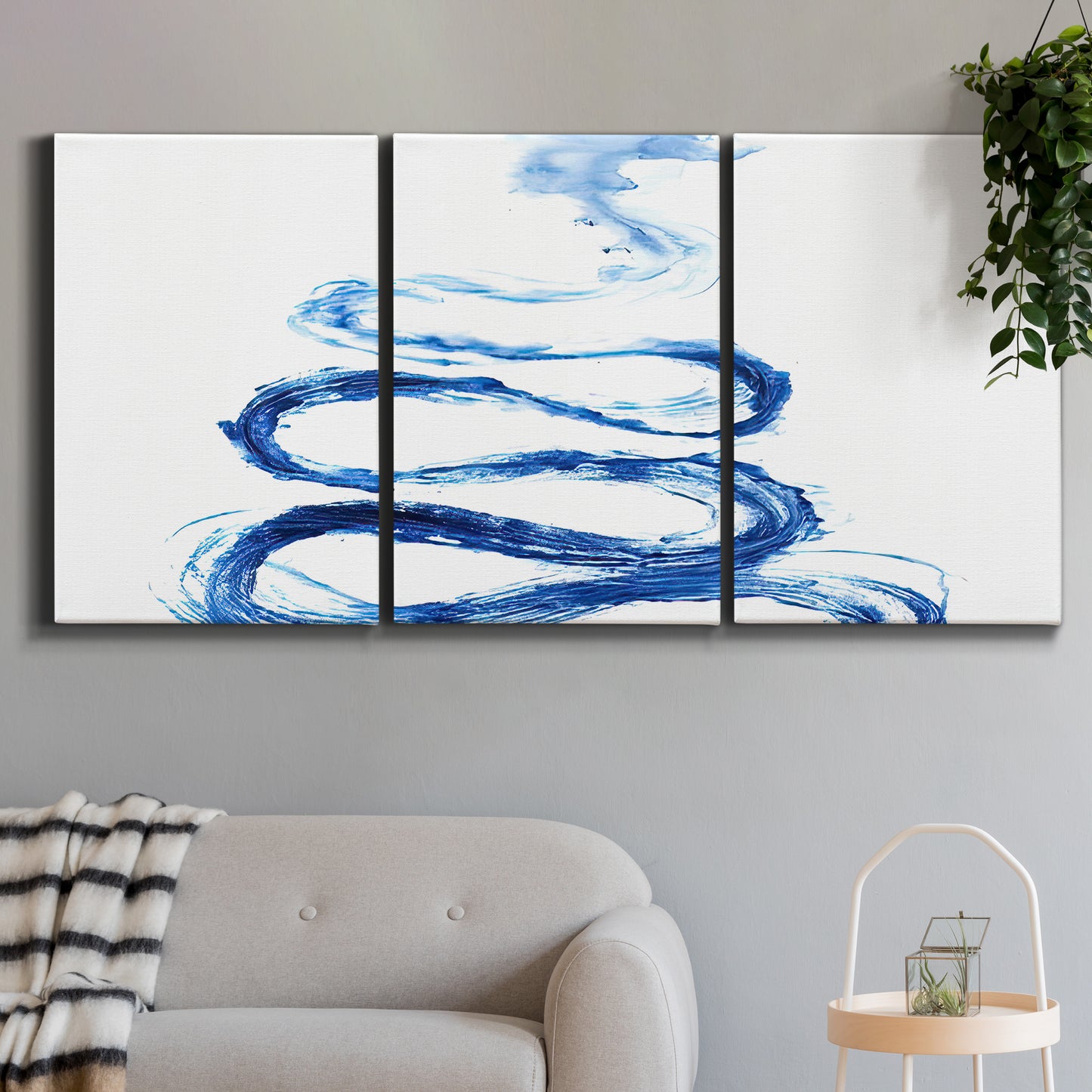 Three-panel canvas wall art featuring indigo abstract vapor watercolor, displayed in a modern living room above a sofa.