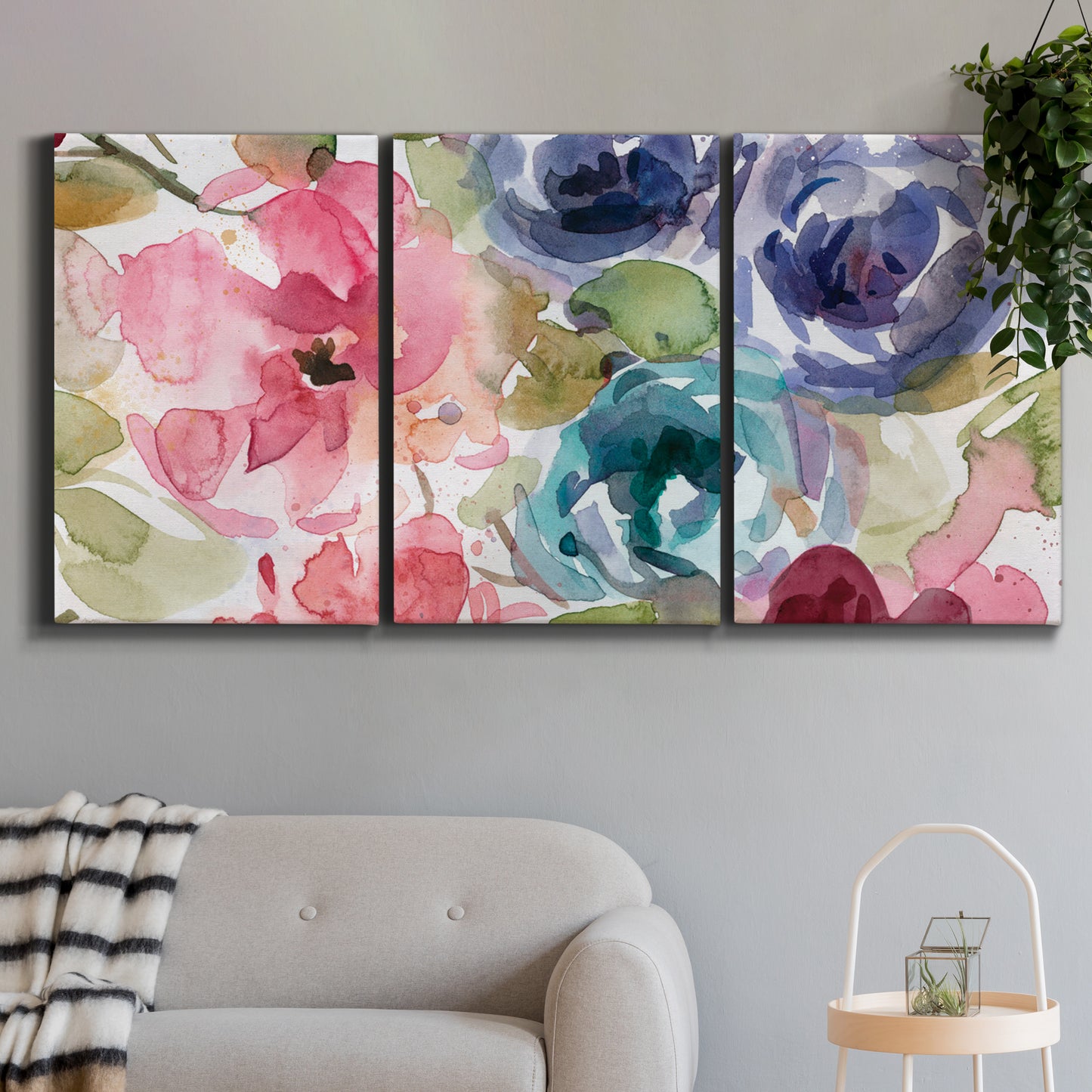 Three-panel canvas wall art featuring soft floral watercolor composition, displayed in a modern living room above a sofa.