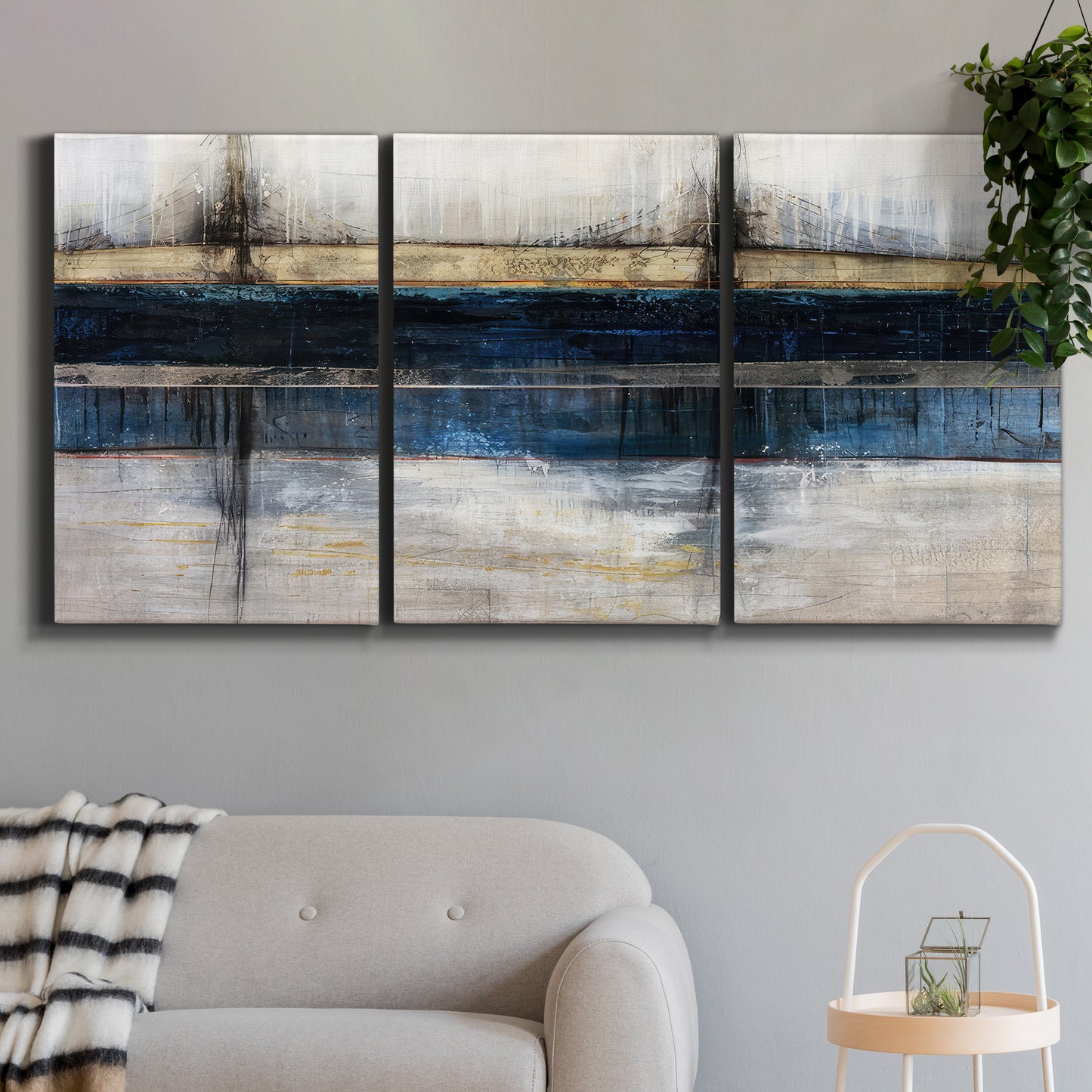 Three-panel canvas wall art featuring abstract blue urban composition, displayed in a modern living room above a sofa.