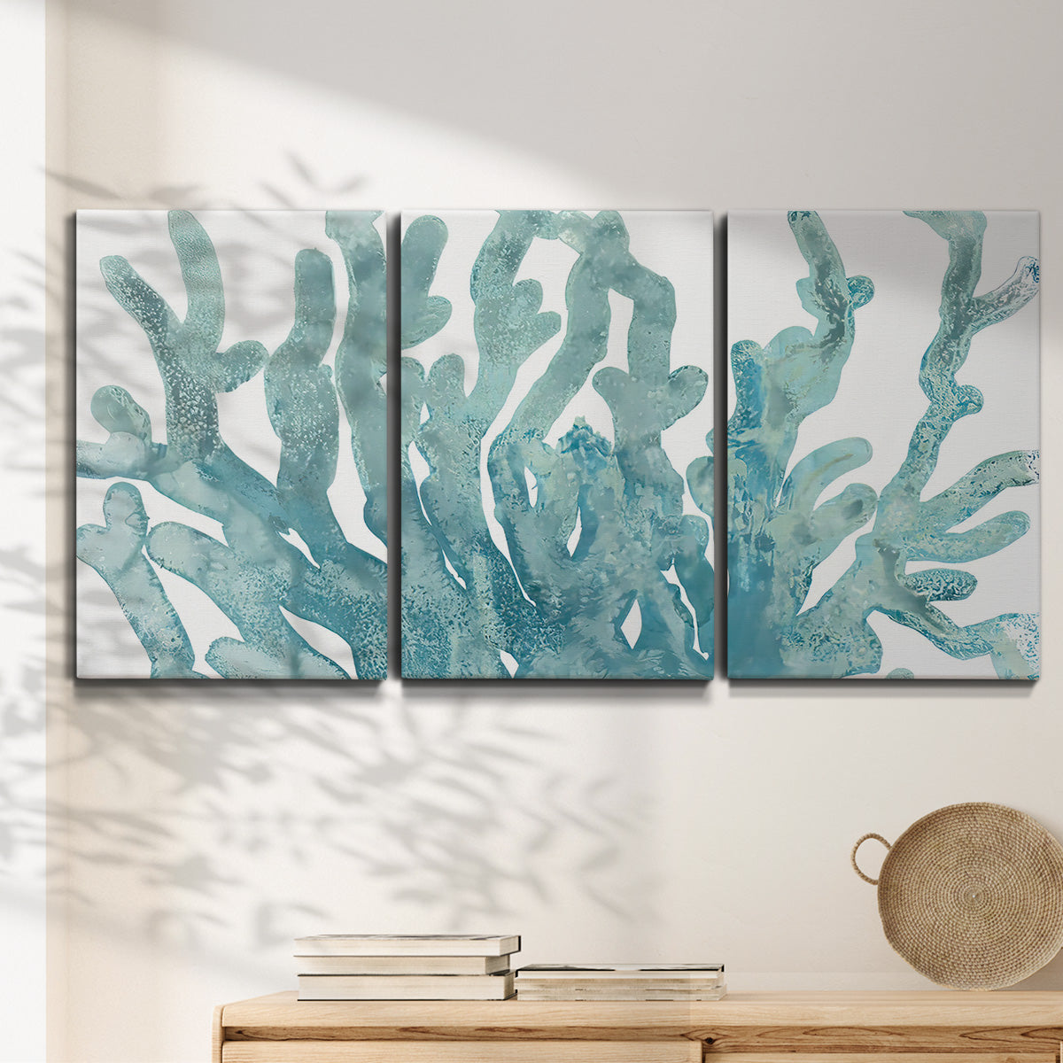 Three-panel canvas wall art featuring blue coral inspired watercolor, displayed in a minimalist living room above a console table.