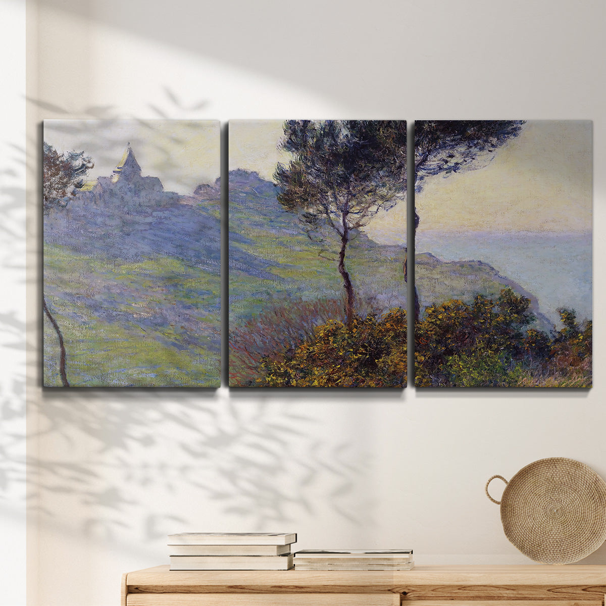 Three-panel canvas wall art featuring village church at sunset, displayed in a minimalist living room above a console table.
