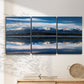 Three-panel canvas wall art featuring calm lake beneath mountains photograph, displayed in a minimalist living room above a console table.