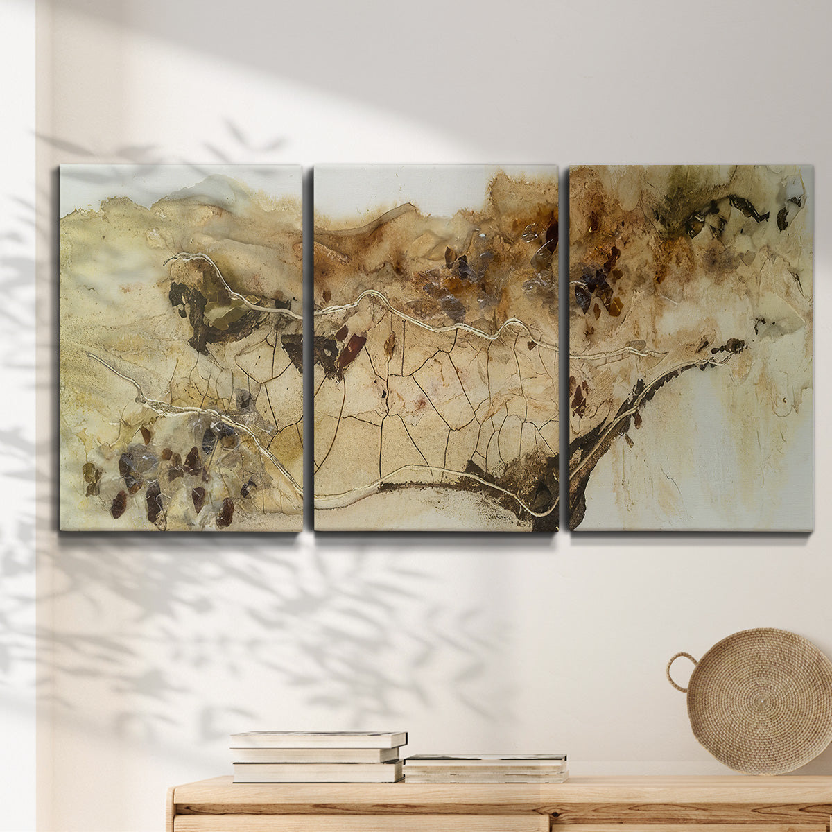 Three-panel canvas wall art featuring muted abstract with metallic gold accents, displayed in a minimalist living room above a console table.