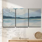 Three-panel canvas wall art featuring soft coastal shoreline landscape, displayed in a minimalist living room above a console table.
