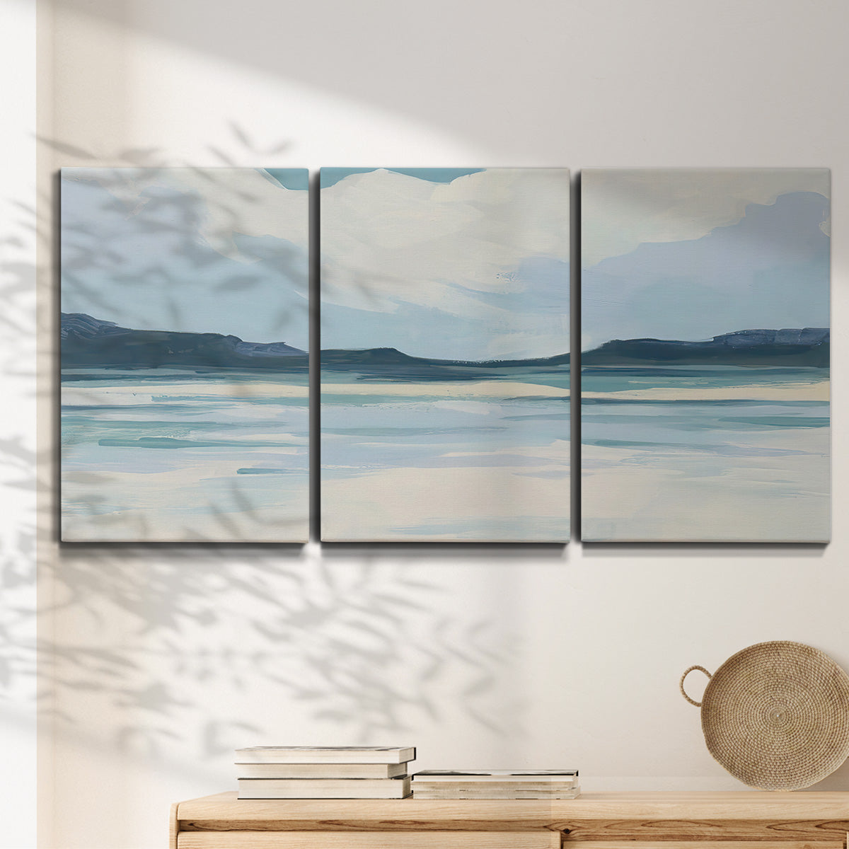 Three-panel canvas wall art featuring soft coastal shoreline landscape, displayed in a minimalist living room above a console table.