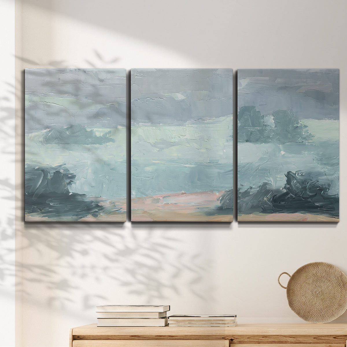 Three-panel canvas wall art featuring soft pastel valley landscape, displayed in a minimalist living room above a console table.
