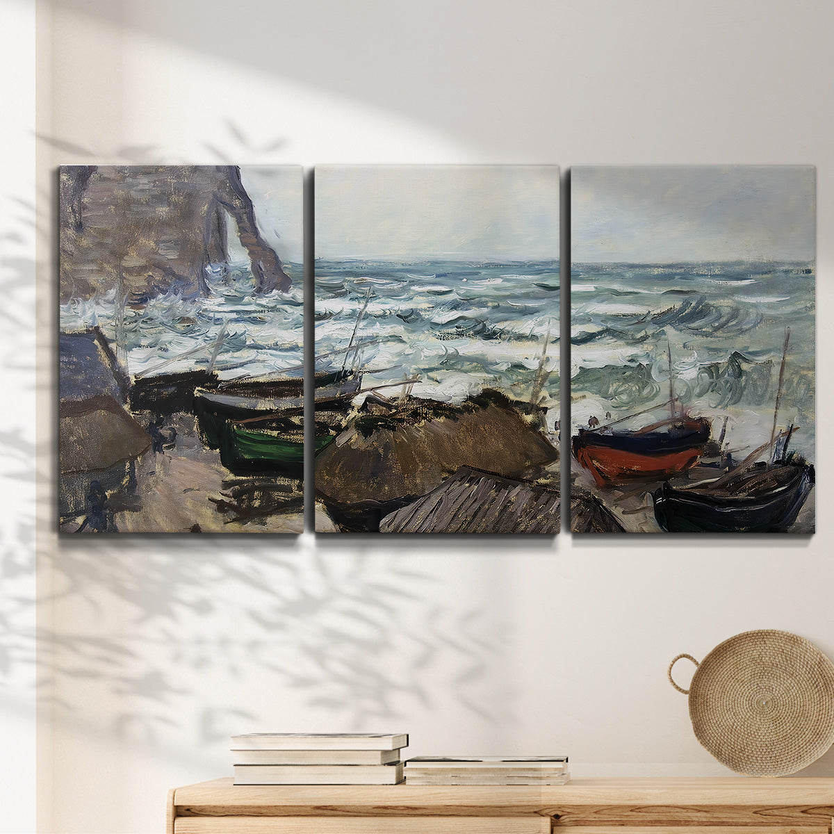Three-panel canvas wall art featuring rough coastal seas under storm clouds, displayed in a minimalist living room above a console table.