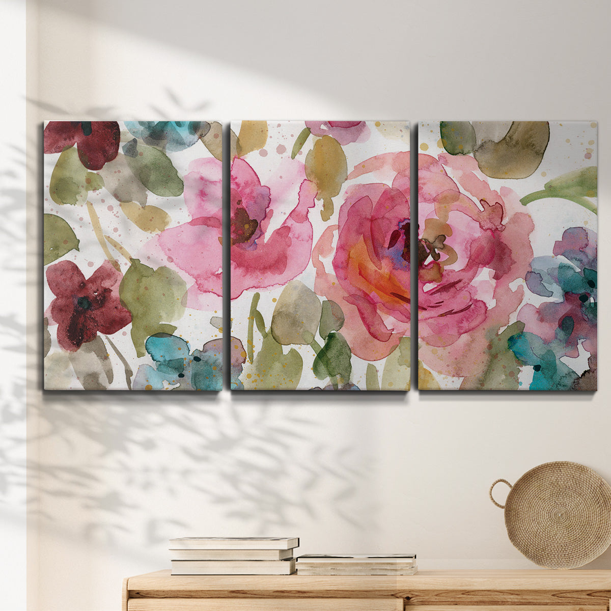 Three-panel canvas wall art featuring colorful floral watercolor composition, displayed in a minimalist living room above a console table.
