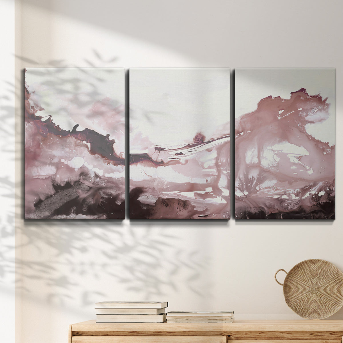 Three-panel canvas wall art featuring soft pink abstract scenic layers, displayed in a minimalist living room above a console table.