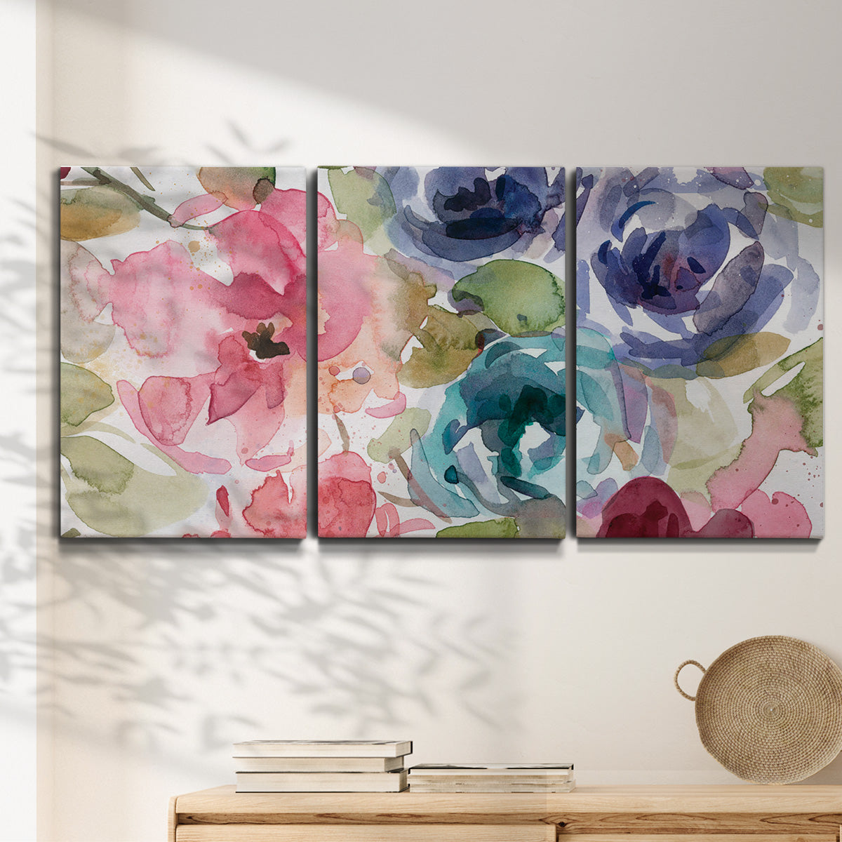 Three-panel canvas wall art featuring soft floral watercolor composition, displayed in a minimalist living room above a console table.