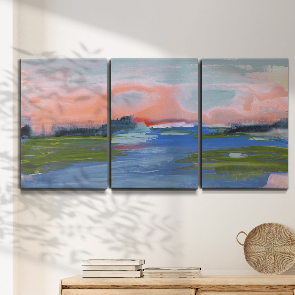 Three-panel canvas wall art featuring sunset reflections across calm sea, displayed in a minimalist living room above a console table.