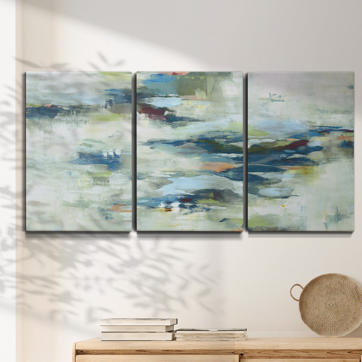 Three-panel canvas wall art featuring dreamlike abstract drifting motion, displayed in a minimalist living room above a console table.