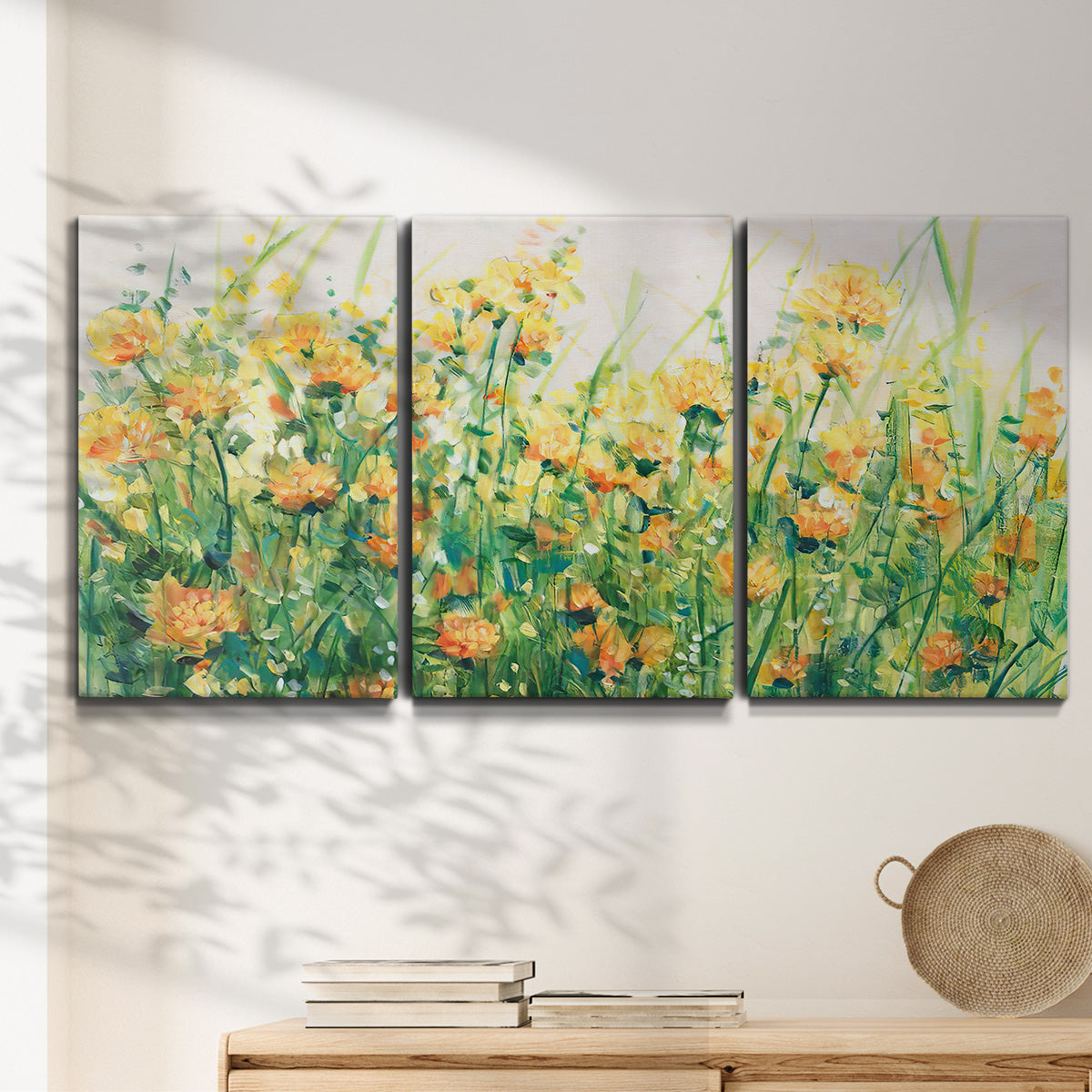 Three-panel canvas wall art featuring colorful garden flowers in bloom, displayed in a minimalist living room above a console table.