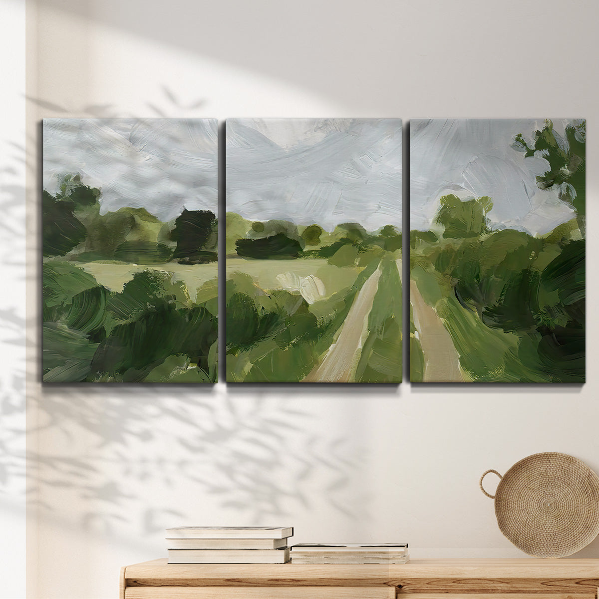 Three-panel canvas wall art featuring meadow trail through open grassland, displayed in a minimalist living room above a console table.