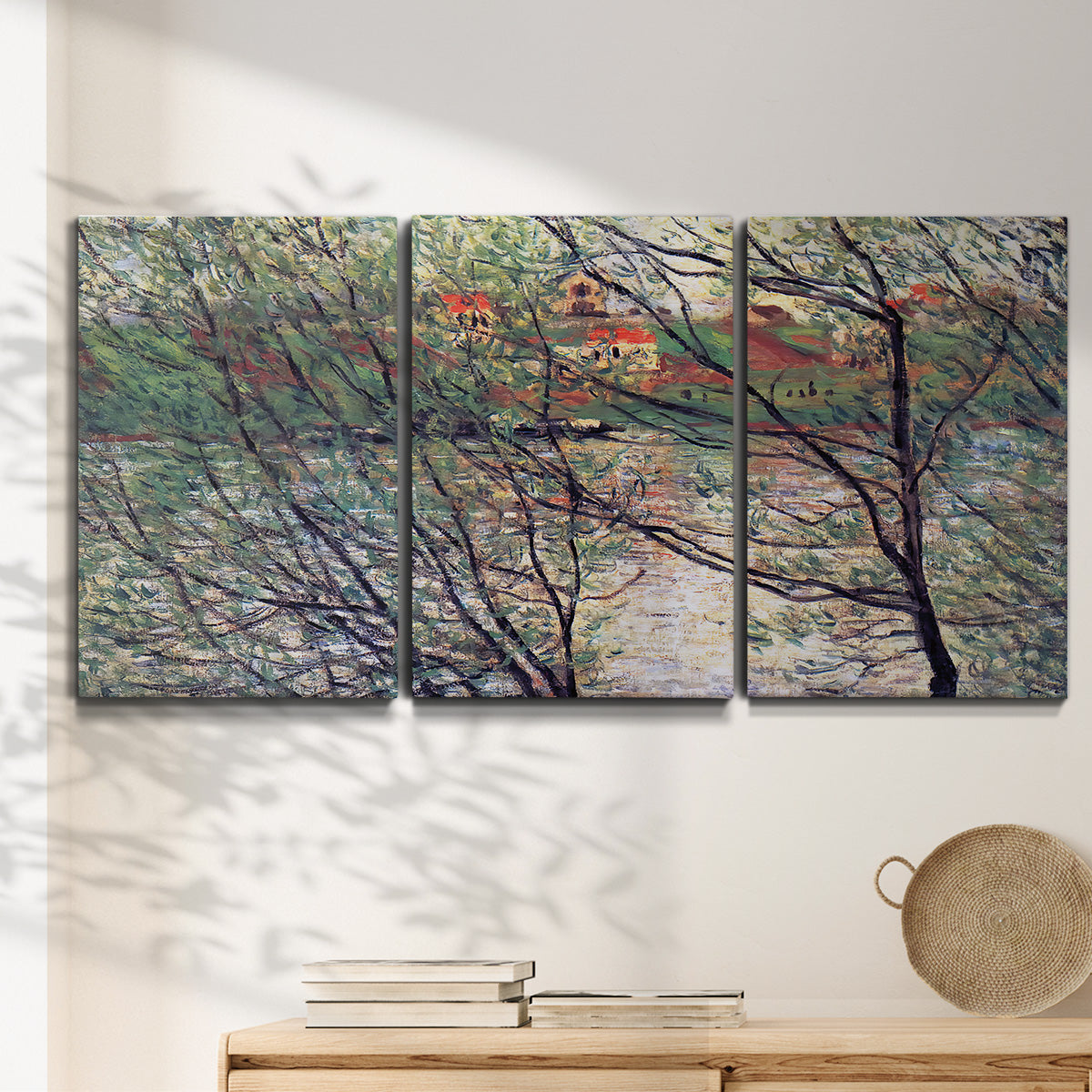 Three-panel canvas wall art featuring riverside park with figures and trees, displayed in a minimalist living room above a console table.