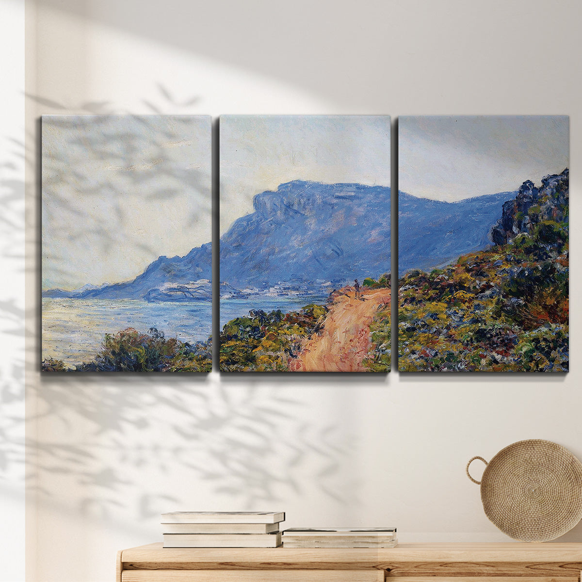 Three-panel canvas wall art featuring winding coastal road above sea, displayed in a minimalist living room above a console table.