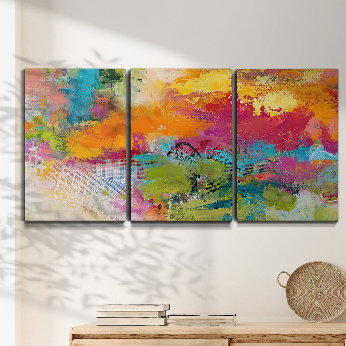 Three-panel canvas wall art featuring expressive abstract sunset tones, displayed in a minimalist living room above a console table.