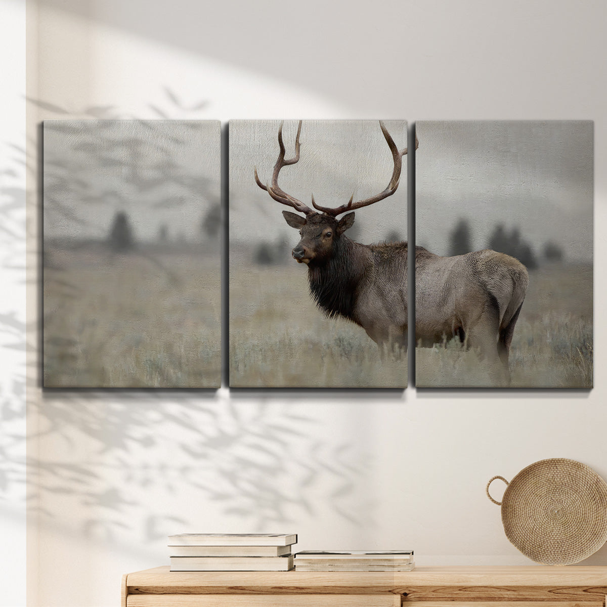 Three-panel canvas wall art featuring elk standing in open grassland, displayed in a minimalist living room above a console table.