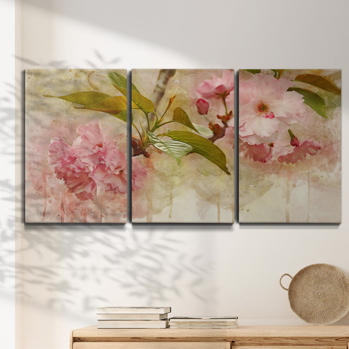 Three-panel canvas wall art featuring soft floral blossom composition, displayed in a minimalist living room above a console table.