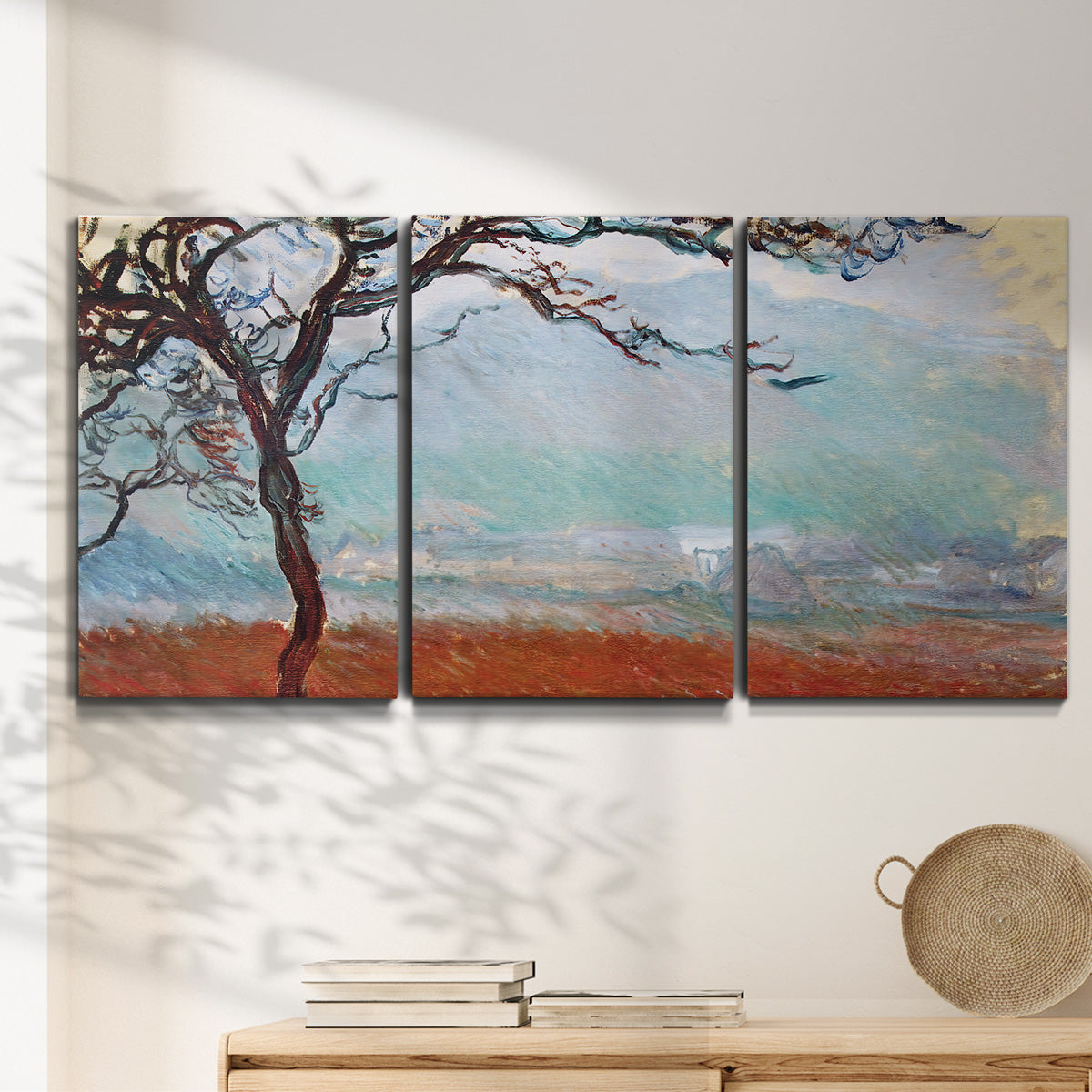 Three-panel canvas wall art featuring coastal trees at evening light, displayed in a minimalist living room above a console table.