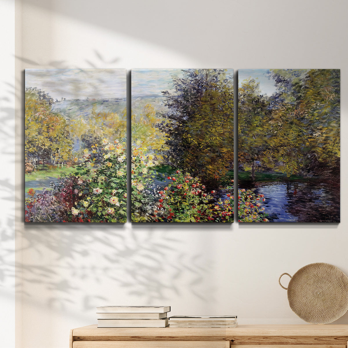 Three-panel canvas wall art featuring garden corner with flowering trees, displayed in a minimalist living room above a console table.
