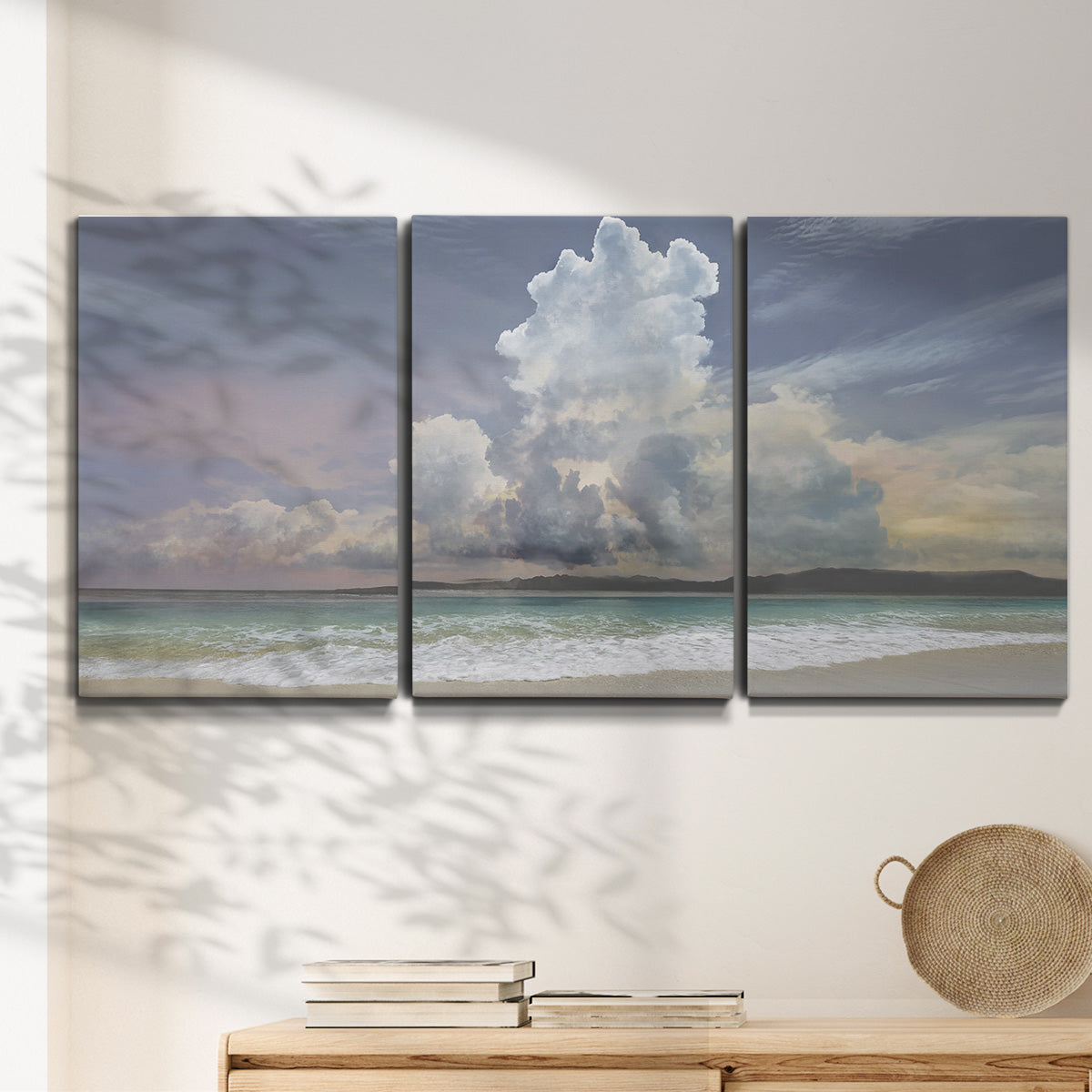 Three-panel canvas wall art featuring rain falling on sandy beach, displayed in a minimalist living room above a console table.