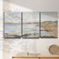 Three-panel canvas wall art featuring coastal shoreline landscape study, displayed in a minimalist living room above a console table.