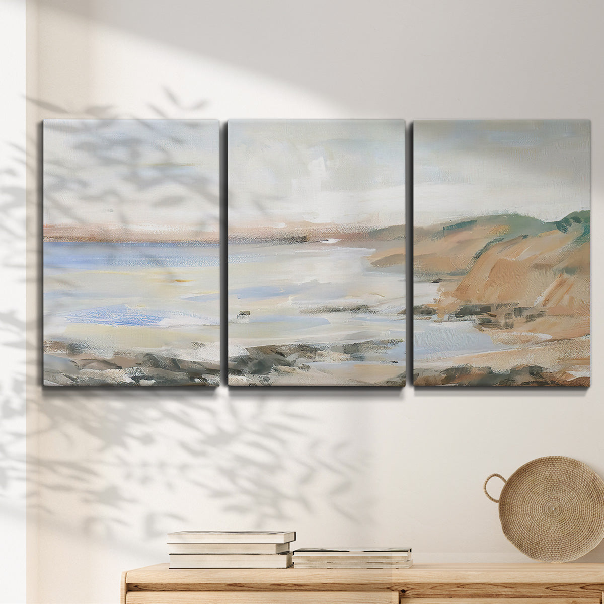 Three-panel canvas wall art featuring coastal shoreline landscape study, displayed in a minimalist living room above a console table.