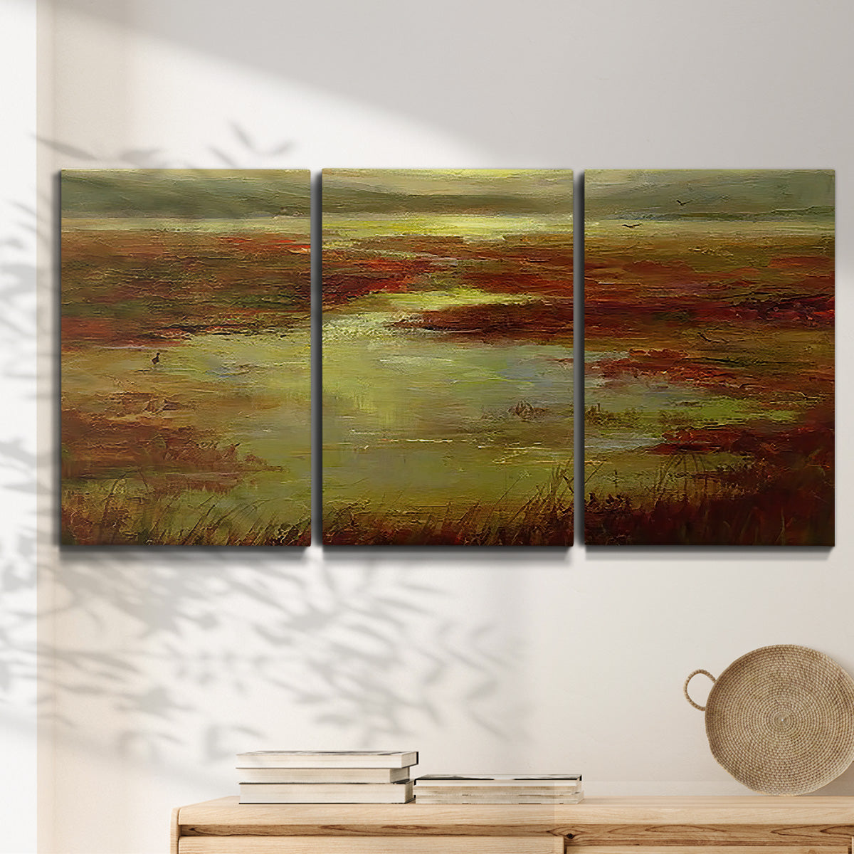 Three-panel canvas wall art featuring coastal shoreline with warm light, displayed in a minimalist living room above a console table.