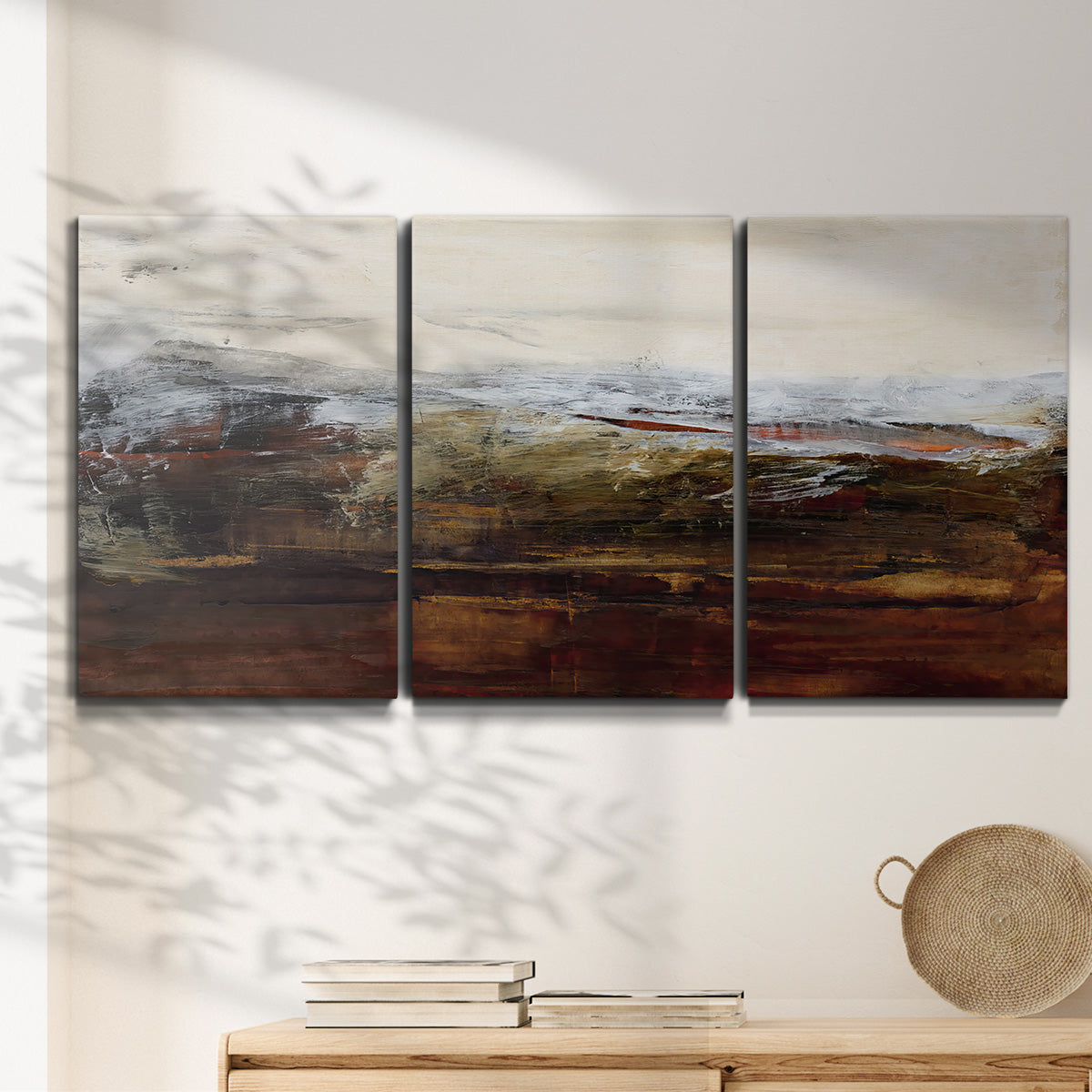 Three-panel canvas wall art featuring rustic abstract landscape exploration, displayed in a minimalist living room above a console table.
