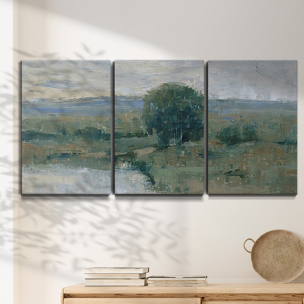 Three-panel canvas wall art featuring riverbank landscape with reflections, displayed in a minimalist living room above a console table.