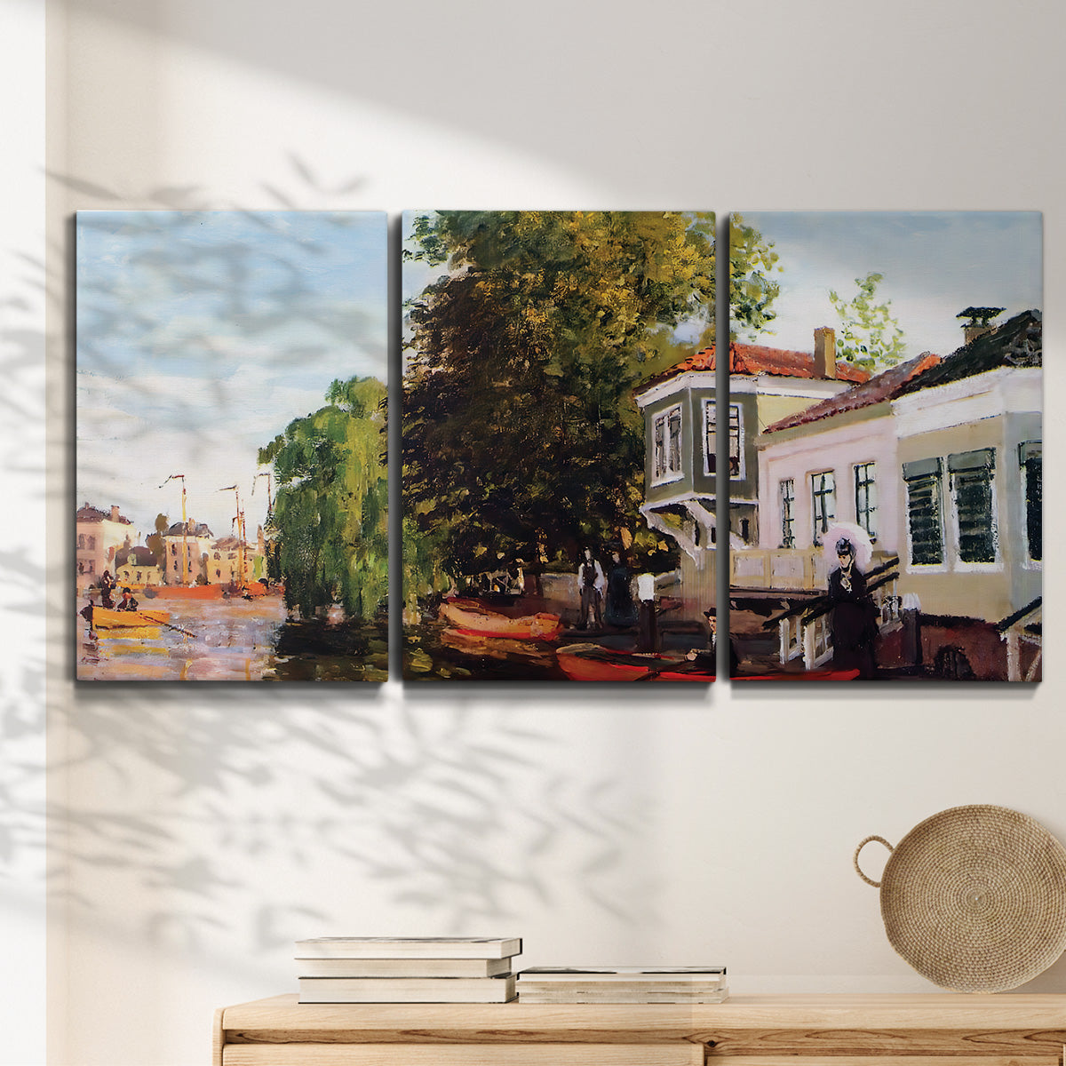 Three-panel canvas wall art featuring riverside houses along canal, displayed in a minimalist living room above a console table.