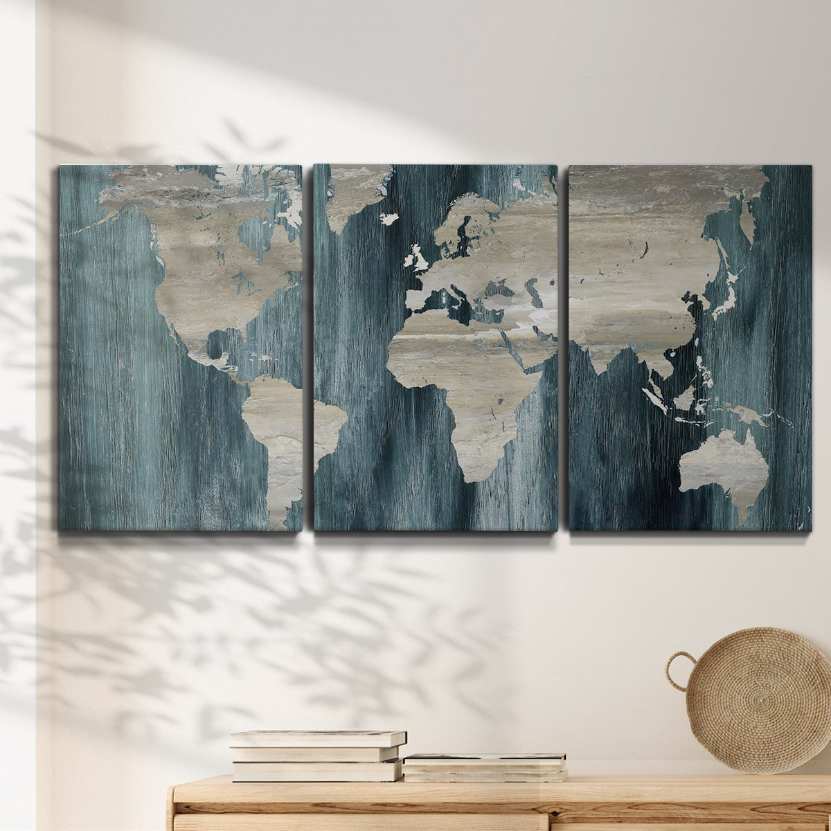 Three-panel canvas wall art featuring golden coastal sunset with cliffs, displayed in a minimalist living room above a console table.