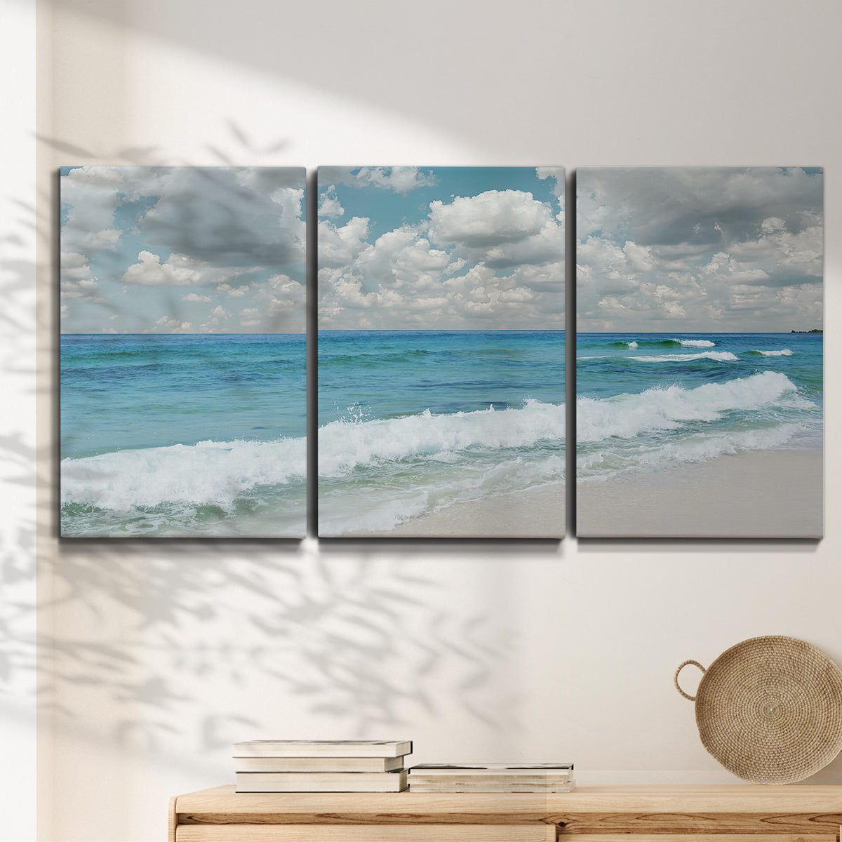 Three-panel canvas wall art featuring tropical beach scene with turquoise water, displayed in a minimalist living room above a console table.