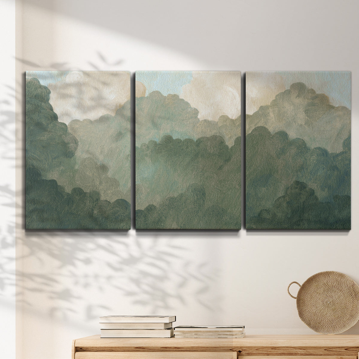 Three-panel canvas wall art featuring autumn storm over rolling landscape, displayed in a minimalist living room above a console table.