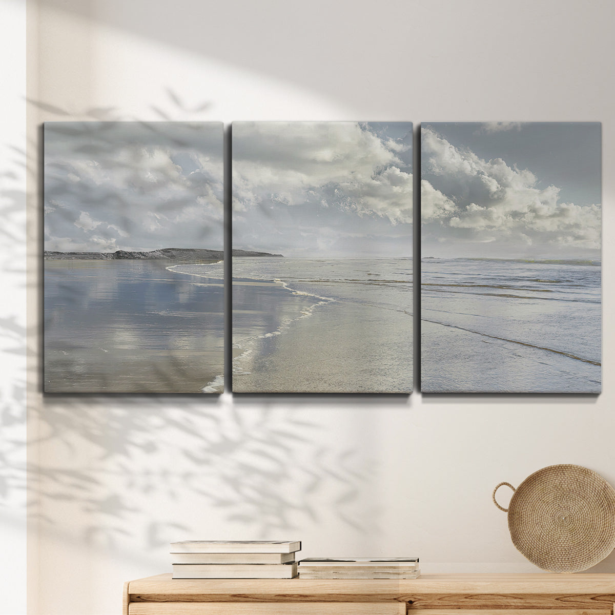 Three-panel canvas wall art featuring endless beach meeting ocean horizon, displayed in a minimalist living room above a console table.