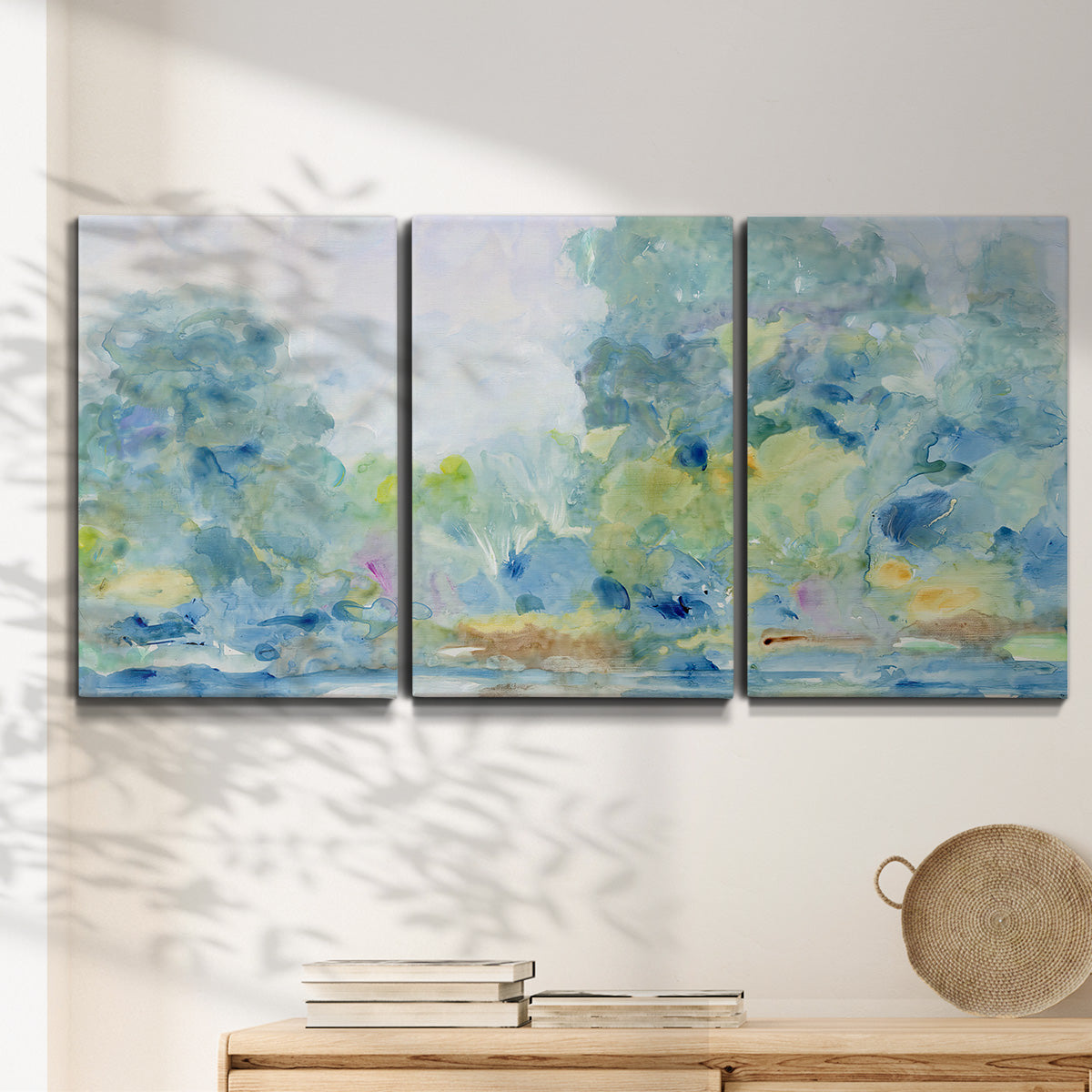 Three-panel canvas wall art featuring quiet abstract morning landscape, displayed in a minimalist living room above a console table.
