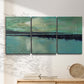 Three-panel canvas wall art featuring calm harbor water with glowing horizon, displayed in a minimalist living room above a console table.