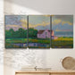 Three-panel canvas wall art featuring farmhouse near coastline landscape, displayed in a minimalist living room above a console table.