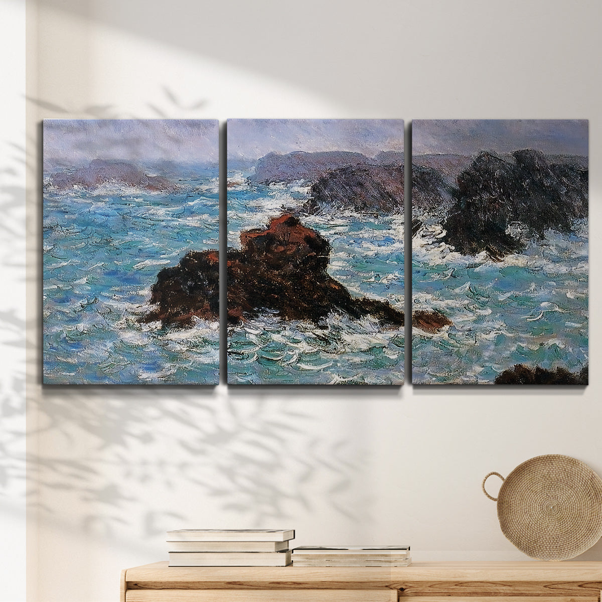 Three-panel canvas wall art featuring storm waves battering rocky coast, displayed in a minimalist living room above a console table.