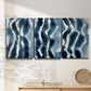 Three-panel canvas wall art featuring flowing blue watercolor wave forms, displayed in a minimalist living room above a console table.